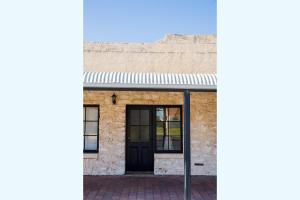 an old brick building with a black door at Duilius in Robe +3 photos