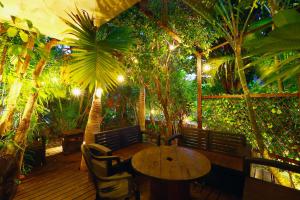a patio with a table and chairs and trees at ゲストハウス303 in Zamami