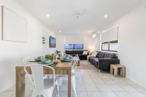 a dining room and living room with a table and chairs at Anchor and Palms in Agnes Water