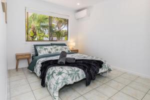 a bedroom with a bed with a blanket and a window at Anchor and Palms in Agnes Water