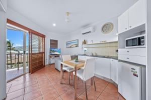a kitchen and dining room with a table and chairs at Spa Haven 17B Ocean View in Airlie Beach +11 photos