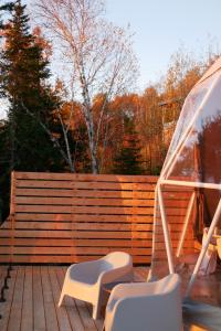 a deck with two chairs and a fence at Nørdika Charlevoix in Baie-Saint-Paul