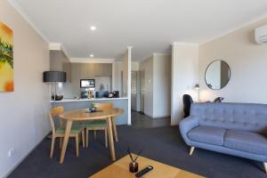 a living room with a blue couch and a table at Quest Tamworth in Tamworth