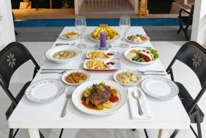 a white table with plates of food on it at De BOUGENVILLE Tulap Beach Front in Watulanei