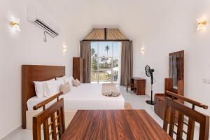 a bedroom with a bed and a desk and a window at Madiha Beach Resort in Matara