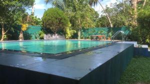 a swimming pool with a fountain in a yard at Feel side villa in Induruwa