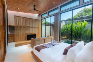 a bedroom with a white bed and large windows at Anasera Villas Echo Beach Canggu in Canggu