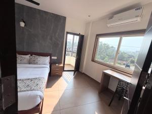 a bedroom with a bed and a desk and a window at Cozy Nook Inn - A BB Linens Experience in Vythiri