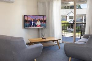 a living room with two chairs and a tv on the wall at Quest Tamworth in Tamworth