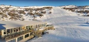 a building in the snow with a snow covered road at Smiggins Hotel & Chalet Apartments in Perisher Valley