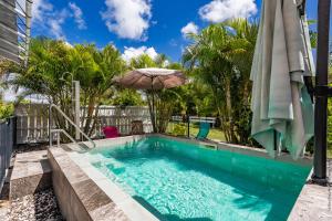 a swimming pool with an umbrella and a swimming poolvisor at Proprizen in Rivière-Salée