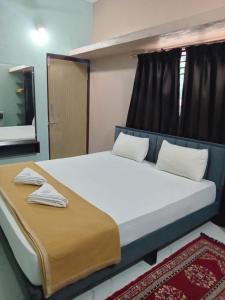 a bedroom with a bed with white sheets and a mirror at The Triple Nest in Gokarna