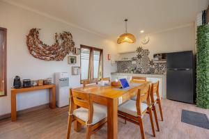 a kitchen with a wooden table with chairs and a refrigerator at Cove Ayuna in Canggu +16 photos