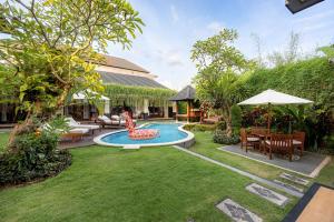 a backyard with a pool with a chair and a table at Cove Ayuna in Canggu