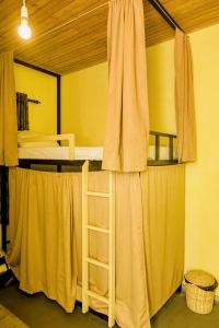 a room with two bunk beds with curtains and a ladder at Wake N Flow, Hiriketiya Beach in Hiriketiya