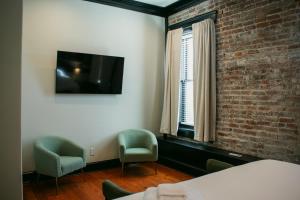 a room with two chairs and a tv and a brick wall at The Montgomery by Visit Apalach in Apalachicola