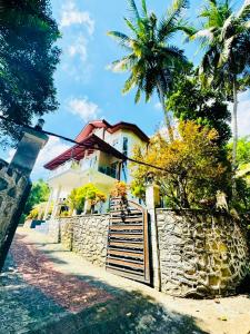 a white house with a fence and palm trees at Sampath Grand Hotel in Mawanella