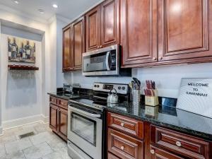 a kitchen with wooden cabinets and a stove top oven at Historic Savannah Condo, Sleeps 6, Pool, Dogs Ok in Savannah