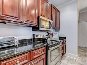 a kitchen with wooden cabinets and stainless steel appliances at Historic Savannah Condo, Sleeps 6, Pool, Dogs Ok in Savannah