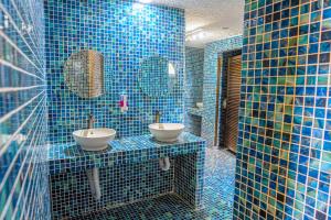 a blue tiled bathroom with two sinks and mirrors at The Social Fortuna in Fortuna