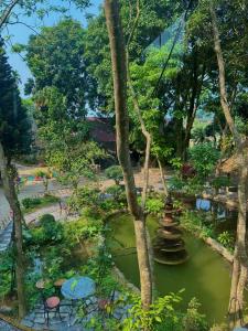 a garden with a pond and trees and a building at Homestay River Green in Làng Lap