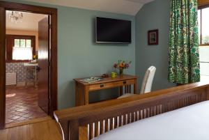 a bedroom with a desk and a television on the wall at Pine Brook Manor in Sparrow Bush