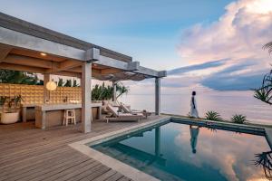 a villa with a swimming pool and a man walking by the ocean at Salty Breeze Amed in Ambat +70 photos