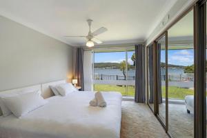 a bedroom with a white bed with a large window at Waterside Escape St Hubert s Island in Saint Huberts Island +23 photos