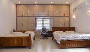 a bedroom with two beds and a chair in it at Aadhya Abode Holiday Home in Kanyakumari