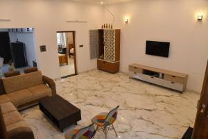 a living room with a couch and a television at Aadhya Abode Holiday Home in Kanyakumari