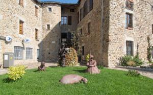 a statue and statues in the grass in front of a building at Maison pierre de mercoeur in Le Malzieu-Ville