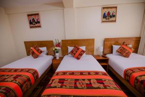 a room with two beds and a vase with flowers at Quechua Hostal Recoleta in Cusco