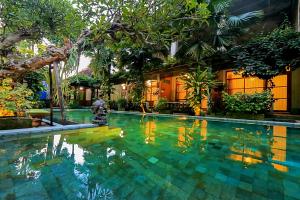 a swimming pool in front of a house with trees at Kalipura Villa - Private Pool & Nature Escape in Bantul