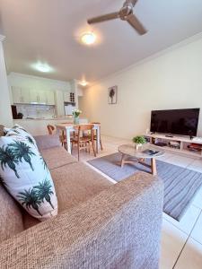 a living room with a couch and a flat screen tv at Reefside Escape Silkari Resort in Port Douglas