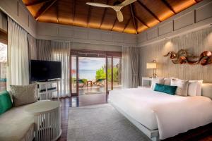 un dormitorio con una cama, un televisor y un sofá en Anantara Rasananda Koh Phangan Villas, en Thong Nai Pan Noi