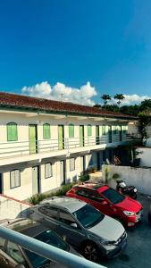 two cars parked in a parking lot in front of a building at Pousada Angellus in Paraty