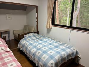 a bedroom with a bed and a window and a chair at Lodge Jotenki in Kiso