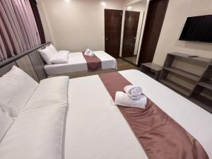 two beds in a hotel room with towels on them at Cambridge Guest House in Mandaue City +2 photos