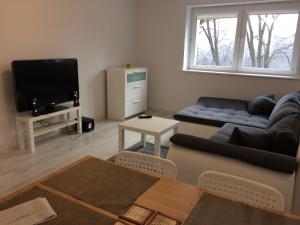 a living room with a couch and a tv at Apartamenty Oaza Spokoju in Sopot