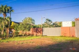 a fence in front of a building with a palm tree at Posada Ña Arminda in Capitán Miranda +6 photos