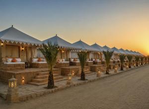 a row of tents with palm trees and lights at Desert Story Night Camp in Jaisalmer