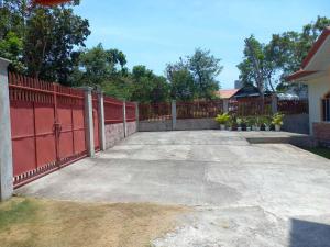 a driveway with a red fence and some plants at Spacious Villa in Baclayon