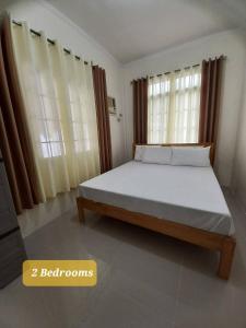 a bedroom with a bed with white sheets and windows at Spacious Villa in Baclayon