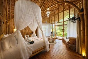 a bedroom with a bed with mosquito netting at Hidden Bamboo Village in Sidemen +89 photos