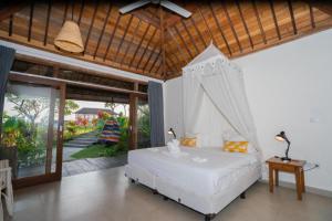 a bedroom with a bed with a mosquito net at Harmony Heaven Ubud by The Travel Ubud Bali in Ubud