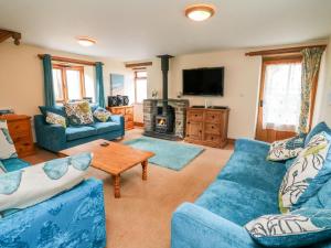 a living room with blue couches and a tv at The Shippon in Barnstaple