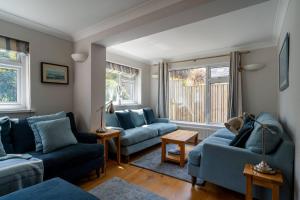 a living room with blue couches and a window at White Sands in Croyde