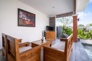 a living room with a table and chairs and a television at Villa Bawa in Ubud