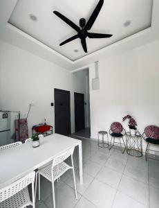 a dining room with a white table and a ceiling fan at CasaView Beach in Paka
