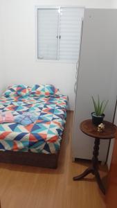 a bedroom with a bed and a table with a plant at Apartamento Compacto Localização Privilegiada in Uberaba